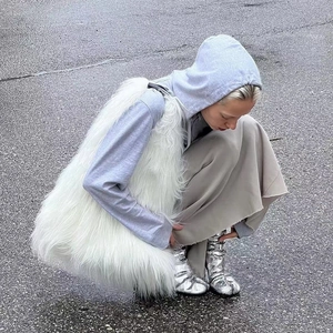 Street style view of high-quality white faux fur vest paired with metallic silver boots