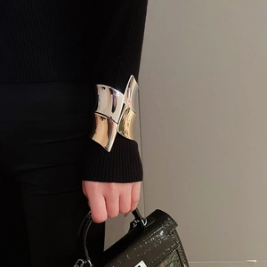 Dettaglio di un largo bracciale bicolore in metallo oro e argento sul polso