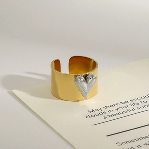 Detail of a two-tone wide open ring featuring a silver heart on a golden band
