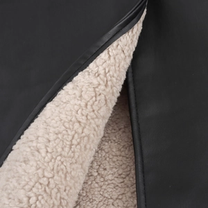 Dettaglio della spessa fodera in shearling beige e della trama in pelle nera sul cappotto