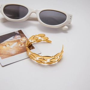 Detailed view of golden open cuff bracelet with hammered hollow triple fish design