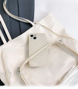 Dettaglio della borsa tote crema con tasca frontale in PVC trasparente e smartphone