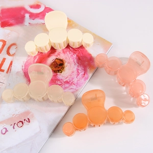 Detail view of four bubble-shaped hair claws in cream, beige, pink, and orange plastic