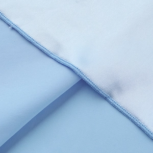 Macro du tissu satiné bleu clair avec couture overlock précise et texture textile raffinée
