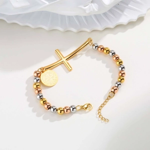 Detail of tricolor beaded bracelet with gold cross and Saint Benedict medal charm