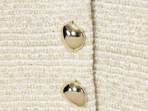 Vue macro du tissu en tweed avec deux boutons en métal doré poli sur un gilet beige