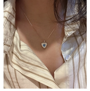 Close-up of S925 silver heart necklace with blue zircon on a woman's collarbone
