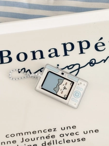 Close-up of camera-shaped acrylic keychain with blue cat design on white tray