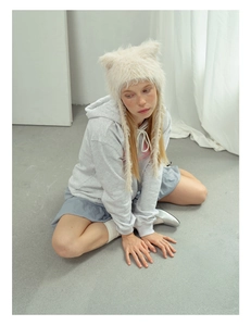 Detail view of cream plush cat-ear hat paired with a grey drawstring hoodie and silver shoes