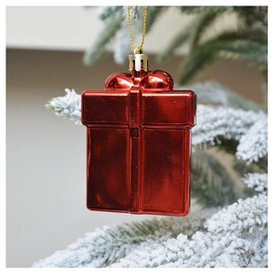 Macro shot of mirror red gift box ornament hanging on snow-covered pine branch
