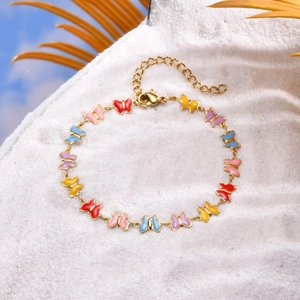 Detailed macro view of gold chain bracelet with colorful enamel butterfly charms