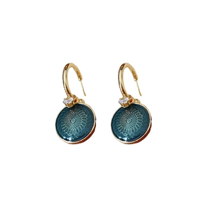 Vintage gold flower earrings with deep green round pendants and zircon stones on white background