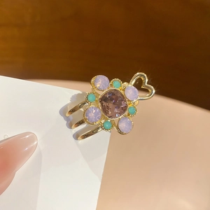 Détail d'une pince à cheveux dorée avec pierres violettes et motif cœur