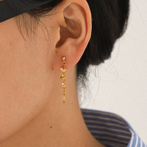 Close-up of 18k gold plated stainless steel long chain tassel earrings on model ear