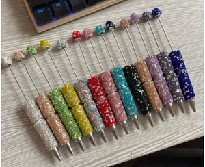Flat lay of colorful crystal bead pens with luxury rhinestone finish on a desk