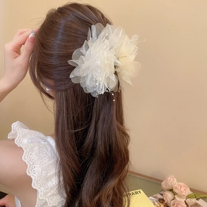 Detail of elegant off-white mesh flower hair claw clip with pearl on long wavy hair