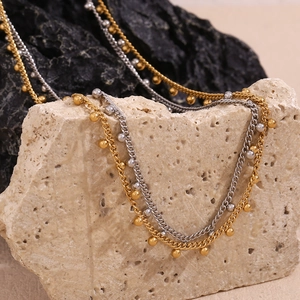 Detail of layered gold and silver chains with small metal beads on stone display