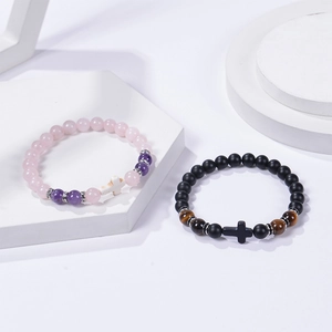 Détail de bracelets en quartz rose 8mm et œil de tigre avec croix sur des socles blancs