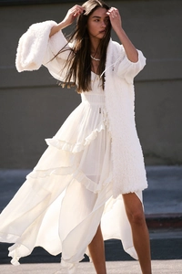 Detailed view of white ruffled lace split dress with bohemian tiered flowing fabric