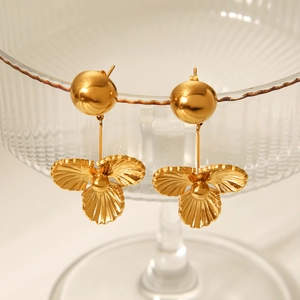 Détail de boucles d'oreilles pétales en acier doré 18 carats sur un verre