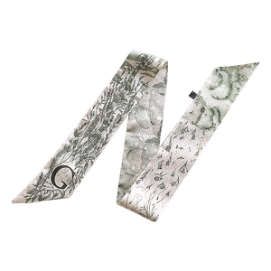Macro view of green floral silk ribbon scarf with elegant alphabet G printed pattern