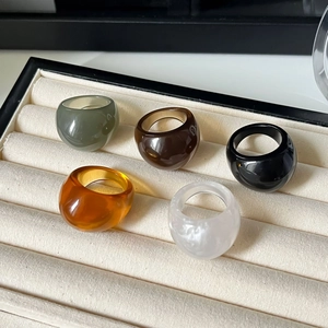 Set of 5 colorful vintage resin rings in amber, green, and marble on a jewelry display box