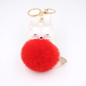 Detail of fox head keychain with red faux fur pom-pom and golden lobster clasp