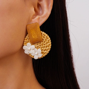 Macro view of handmade round rattan earrings with white fabric flower on model ear