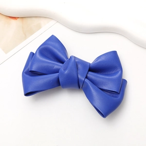Close-up of a handmade navy blue faux leather bow accessory with detailed texture and pleats