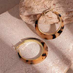 Close-up of leopard resin hoop earrings with elegant gold accents on stone base