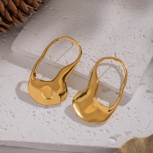 Minimalist geometric gold earrings with molten metal design on a stone background