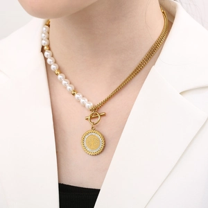 Close-up of 18K gold-plated necklace with white pearls, tree of life pendant and T-bar clasp
