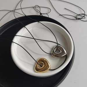 Macro detail of gold and silver heart pendants on a black wax cord necklace