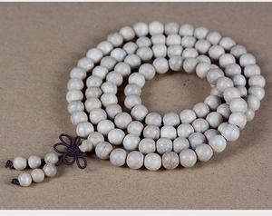 Macro detail of natural camphor wood prayer beads with traditional silk tassel on kraft paper