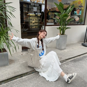 Black and white striped canvas tote bag styled with a white street outfit on a model