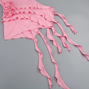 Detail of pink dress featuring 3D rose applique, ruffled layers and elegant flowing ribbons