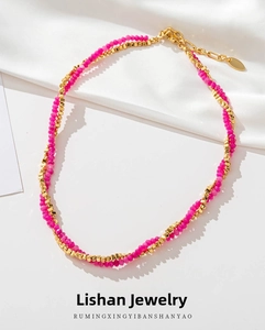 Detail of beaded necklace with faceted pink stones and golden cubes on white silk fabric