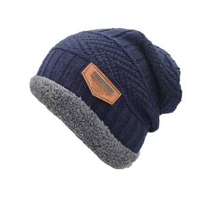 Bonnet en maille torsadée bleue avec doublure en fausse fourrure grise sur fond blanc