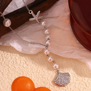 Detailed macro view of silver necklace with pearl beads, starfish, and rhinestone scallop charm