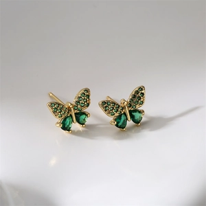 Detail of gold butterfly earrings featuring vibrant green rhinestones and teardrop gems