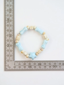 Detailed view of ceramic bracelet with blue bone-shaped beads next to a measuring ruler