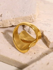 Close-up of golden irregular wavy ring with brushed metal texture on natural stone