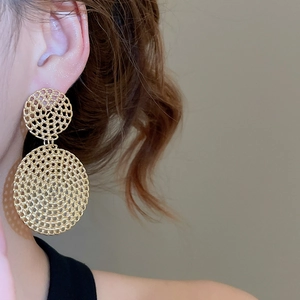 Close-up of gold double-circle woven pendant earrings worn on a female model