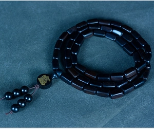 Macro view of dark sandalwood square beads with a golden character accent bead