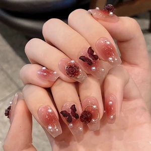 Detailed view of nude pink gradient press-on nails with 3D roses, butterflies and pearls
