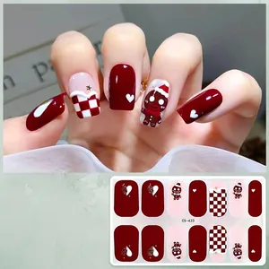 Macro view of Christmas gingerbread man and checkered pattern gel nail stickers