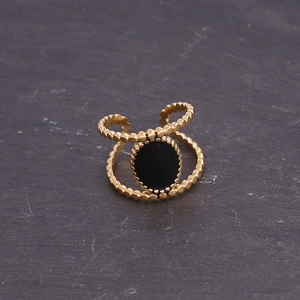 Detail of gold beaded band ring featuring a round black stone inlay on stone texture
