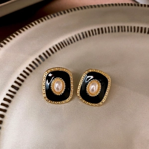 Vintage gold plated square stud earrings with black enamel and pearl center on tray