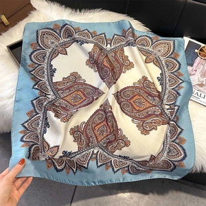 Détail d'un foulard carré en soie à imprimé paisley avec bordures bleu clair et crème