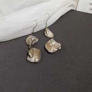 Dettaglio di orecchini pendenti in argento con madreperla dalla trama iridescente
